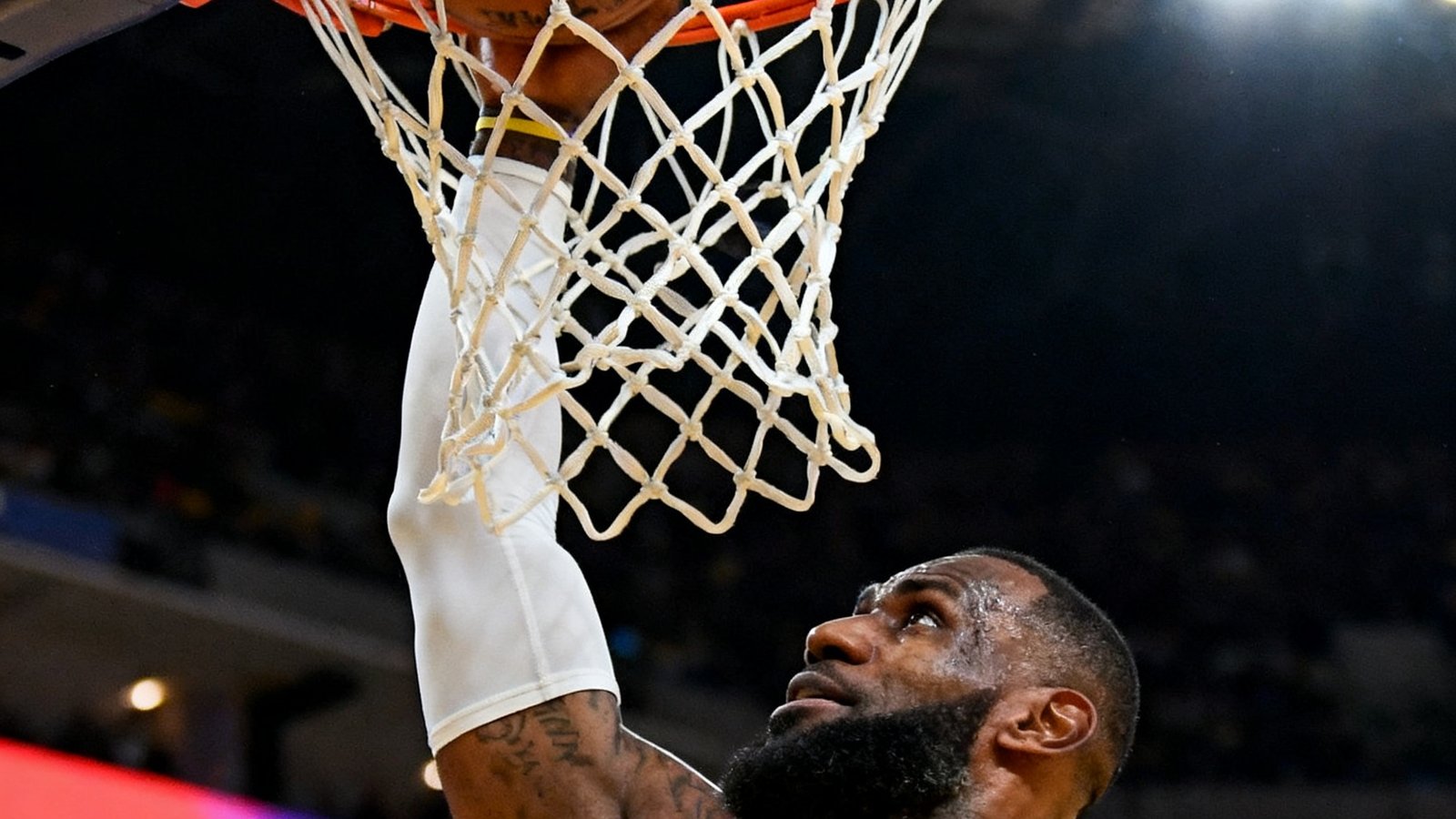 NBA湖人队詹姆斯在对阵勇士比赛中完成一记精彩扣篮的瞬间，篮筐特写画面极具冲击力